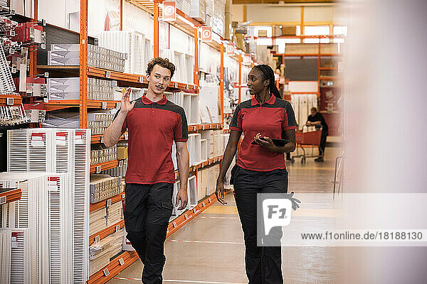 Male and female sales staff talking while walking in hardware store