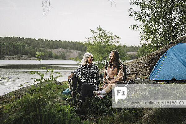 Lächelnde ältere Frauen  die sich auf einem Felsen sitzend beim Camping unterhalten