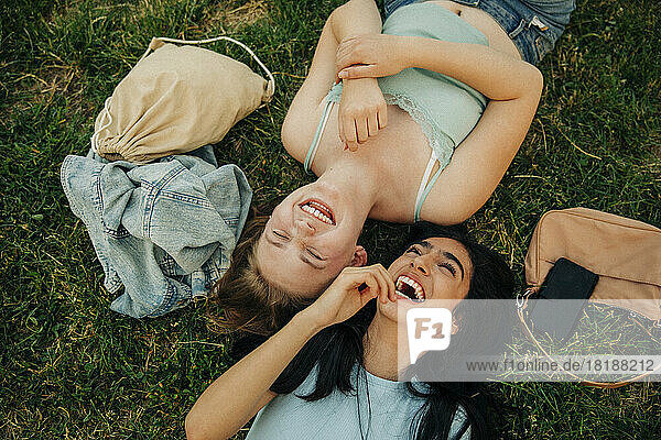 Cheerful teenage girls lying together at park