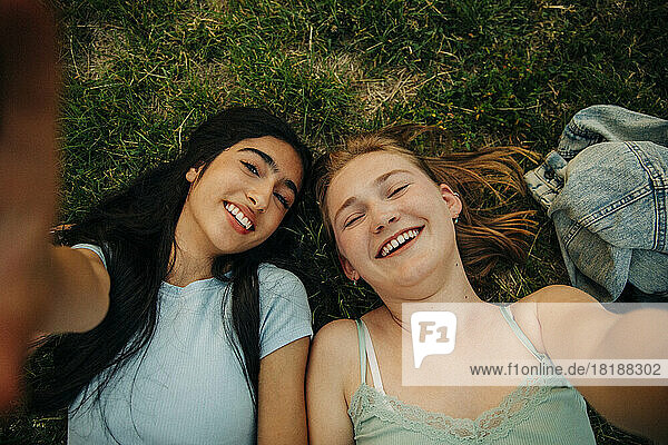 Porträt von glücklichen Teenager-Mädchen  die im Park auf dem Gras liegen