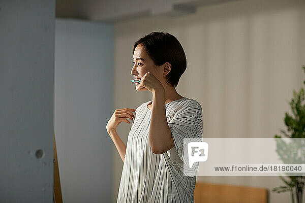 Japanese woman brushing teeth at home