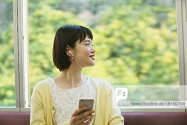 Young Japanese woman listening to music on the train