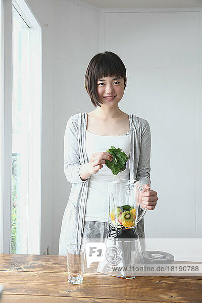 Young Japanese woman making a green smoothie