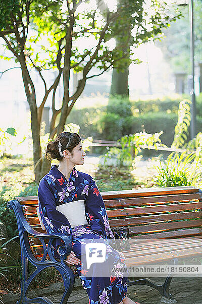 Japanese woman in a yukata sitting on a bench