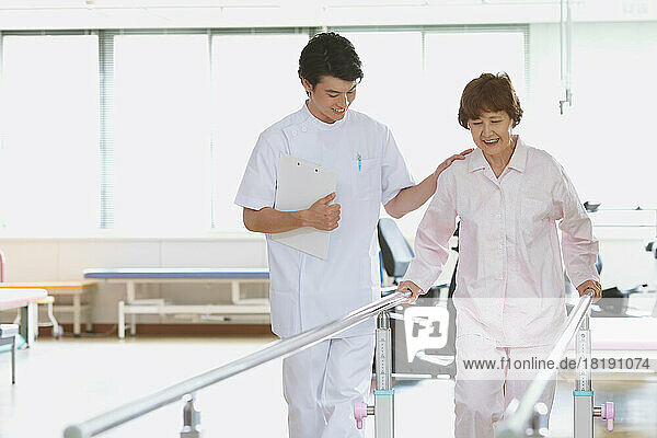 Senior Japanese woman and young male nurse in rehab facility