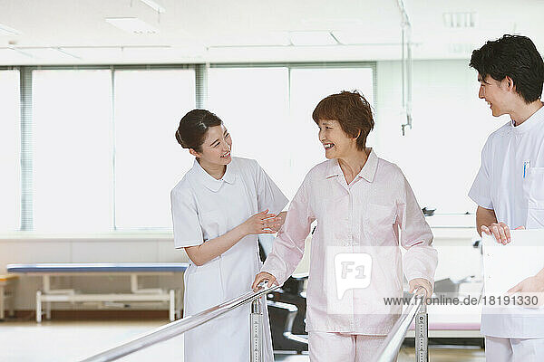 Smiling Japanese senior woman and young nurses in rehab facility