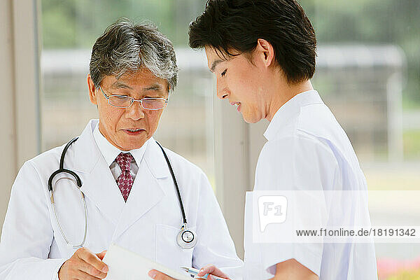 Japanese doctor and a young male nurse having a conversation in the hallway