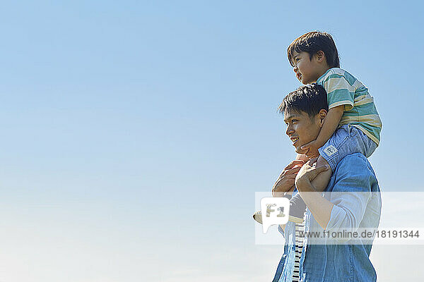 Japanese father carrying his son on his shoulders