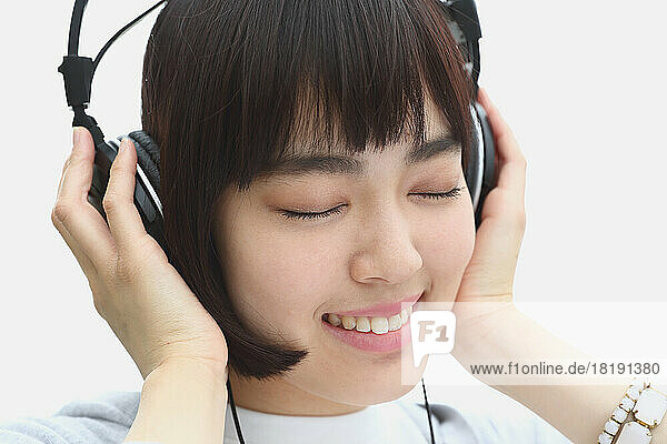 Young Japanese woman listening to music with headphones