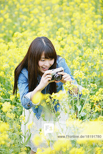 Young Japanese woman taking pictures in a field of blossoms
