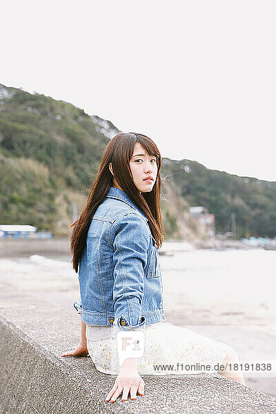 Young Japanese woman sitting on the sea barrier