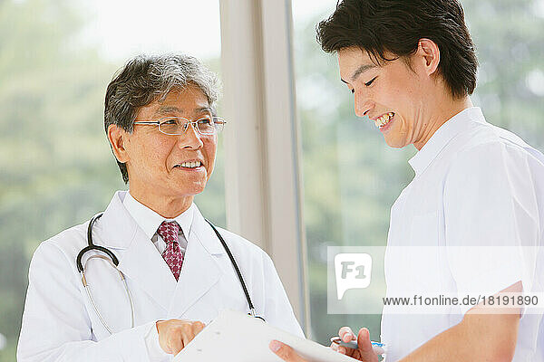 Japanese doctor and a young male nurse having a conversation in the hallway