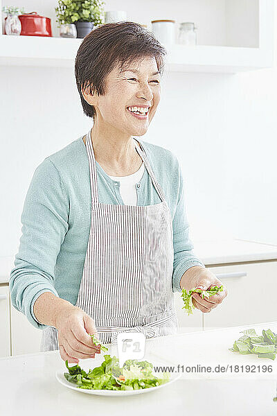 Japanese senior woman serving salad