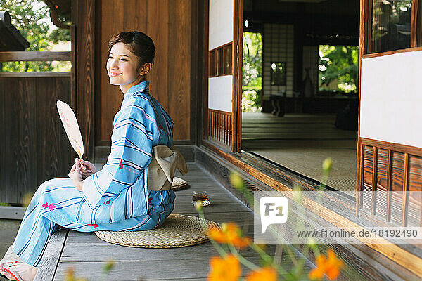 Japanese woman in a yukata cooling off on the porch