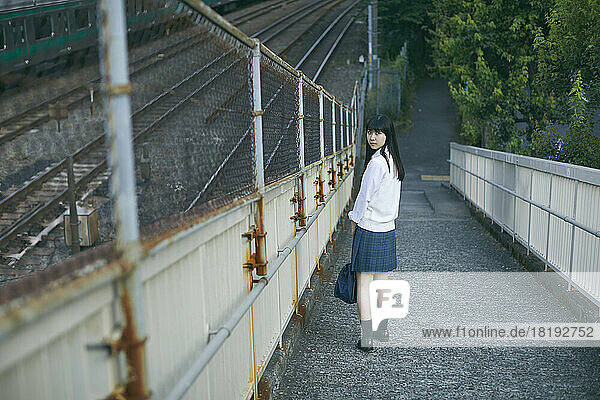 Japanese high school girl on a pedestrian bridge