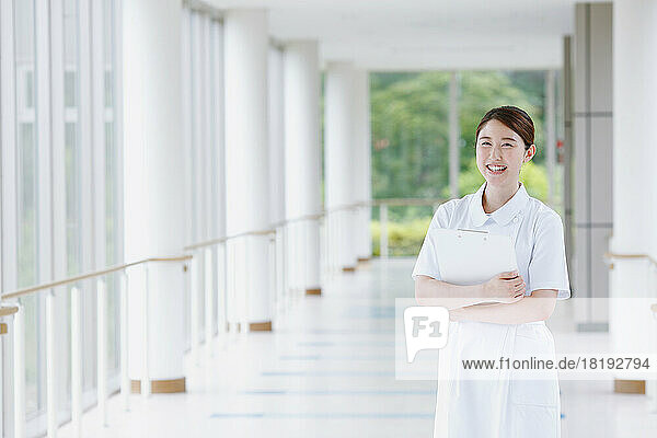 Smiling young Japanese female nurse walking in the hallway