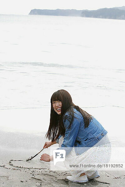 Japanese woman scribbling on the beach