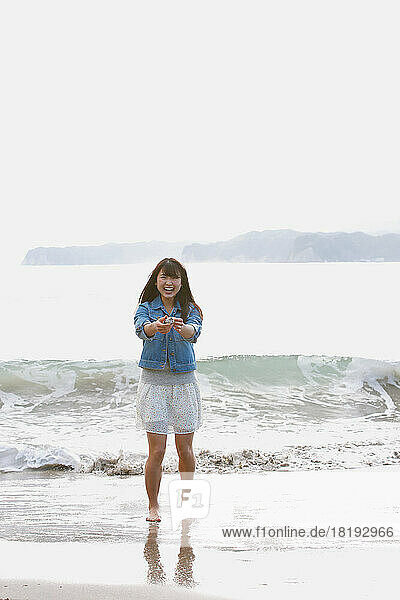 Young Japanese woman collecting shells on the beach