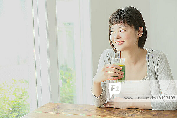 Young Japanese woman drinking green smoothie