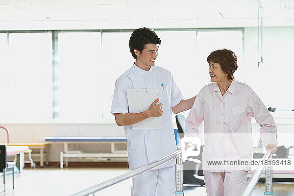 Smiling Japanese senior woman and young male nurse in rehab facility