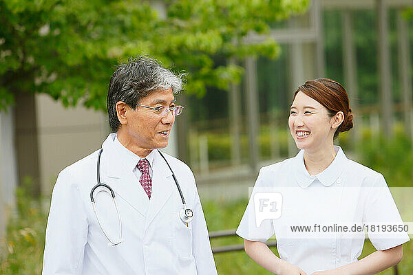Smiling doctor and a young female nurse having a conversation outdoors