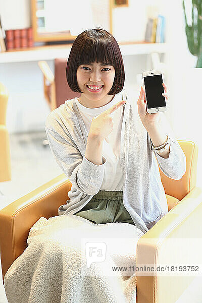Young Japanese woman using mobile phone at beauty salon