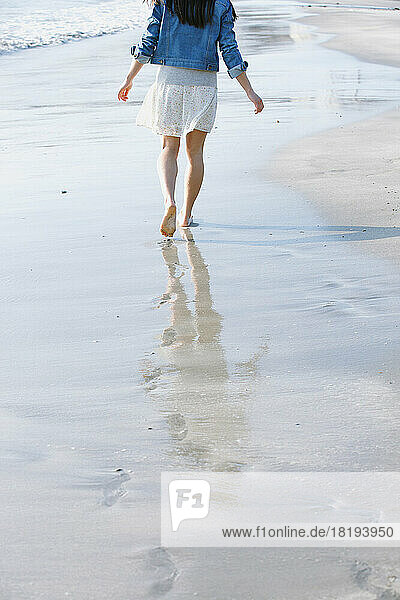 The feet of a young woman walking on the beach