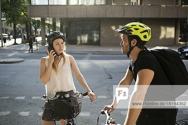 Young man and woman with bicycles on city street