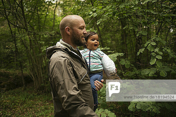 Man holding his daughter while hiking in forest