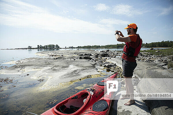 Man with red kayaks on coastal rocks