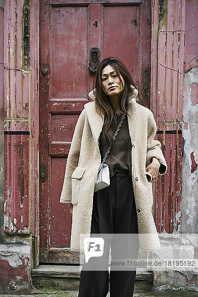 Woman in coat by weathered door