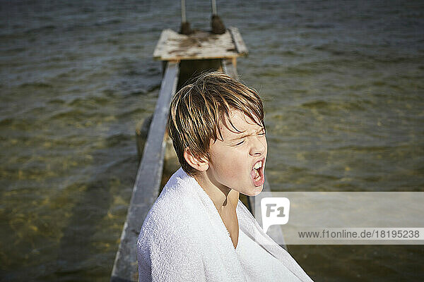 Boy wrapped in towel on jetty