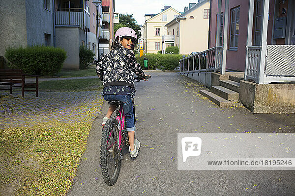 Girl riding bicycle on footpath