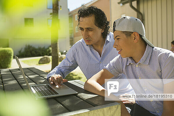 Man helping his son study at outdoor table