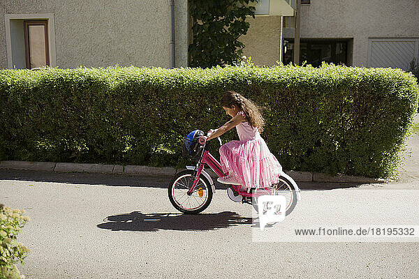 Girl riding bicycle with training wheels