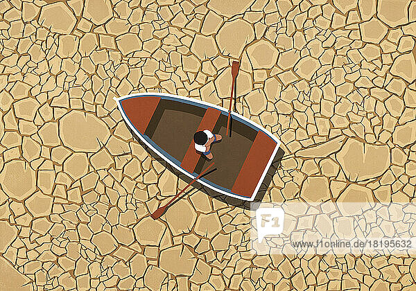 Mann sitzt in Ruderboot auf trockenem  rissigem Land