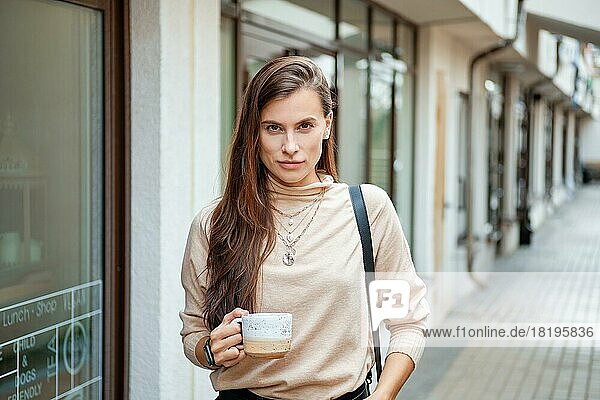 Porträt einer schönen jungen Frau  die im Freien Kaffee trinkt