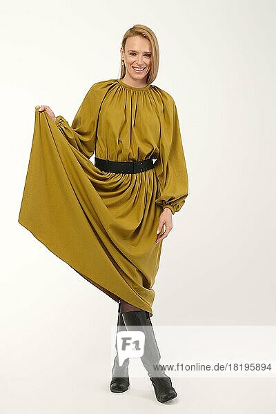 Ganzkörperporträt einer attraktiven Dame in olivfarbenem Kleid auf hellgrauem Hintergrund