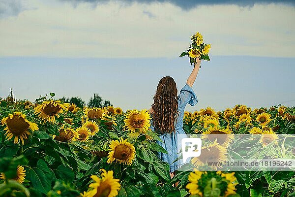Rückansicht einer Frau mit Sonnenblumenstrauß in der Hand