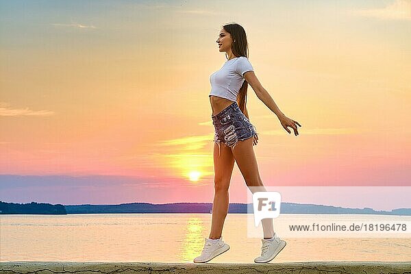 Happy and impetuous young woman enjoys freedom in sunset time