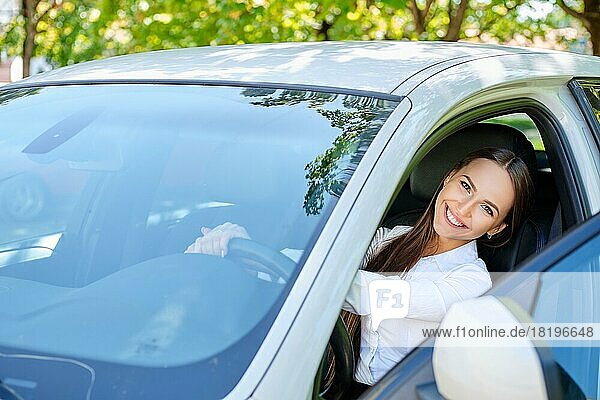 Schönes lächelndes brünettes Mädchen hinter dem Steuer eines Autos