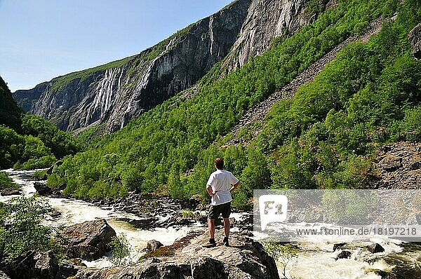 Mann steht in einer Felsenschlucht mit Wasserfall in Norwegen