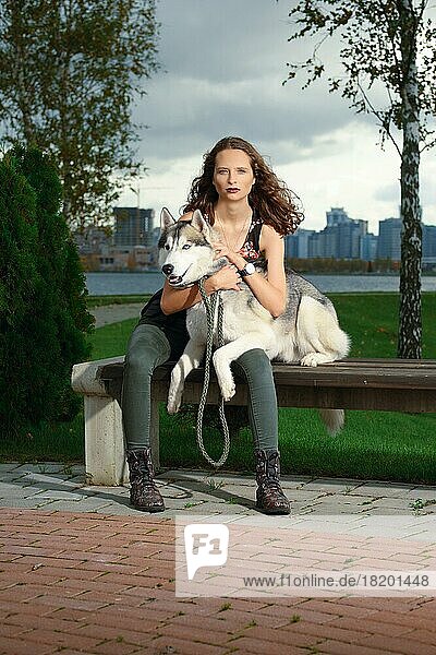 Mädchen mit Husky-Hund im Stadtpark sitzend. Hund auf einer Bank