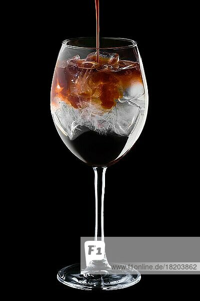 Gießen Spresso in Cocktail mit Tonic in Weinglas vorschwarzem Hintergrund
