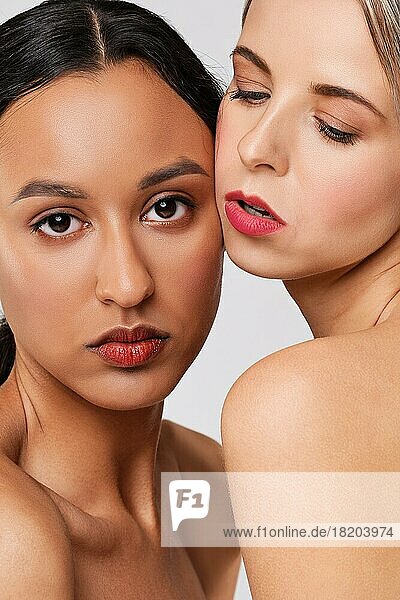 Close up portrait of beautiful african and caucasian young women with perfect skin