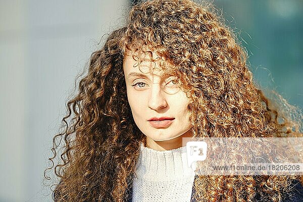 Sonniges Porträt einer Frau mit braunen lockigen Haaren