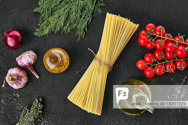 Draufsicht auf rohe Spaghetti mit Gewürzen auf schwarzem Hintergrund