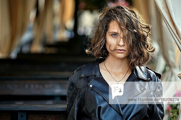 Portrait of beautiful lady with wild curly hair standing near terrace