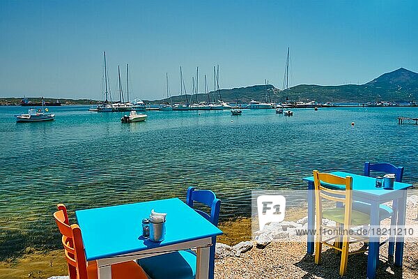 Cafe Restaurant Tisch des Straßencafés mit Stühlen am Strand in Adamantas Stadt auf der Insel Milos mit Ägäischem Meer mit Booten und Yachten im Hintergrund. Insel Milos  Griechenland  Europa