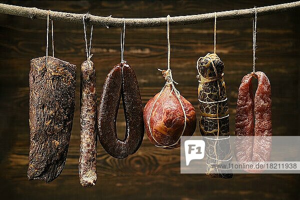Sortiment getrockneter Fleisch- und Wurstwaren  die auf einem Stock in einer Scheune hängen